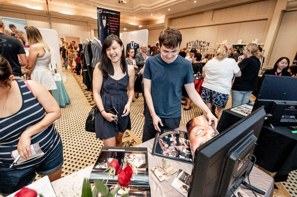 Couples talking with exhibitors across a busy expo floor